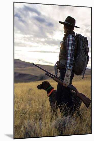 Woman Stands Next To Her Hunting Dog Looking Out Into Montana's Vast Landscape-Hannah Dewey-Mounted Photographic Print