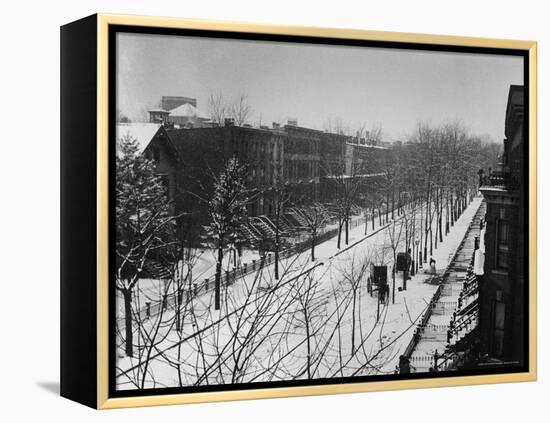 Woman sweeps snow off a snow-covered street lined with brownstones near two horse-drawn buggies.-George B^ Brainerd-Framed Premier Image Canvas