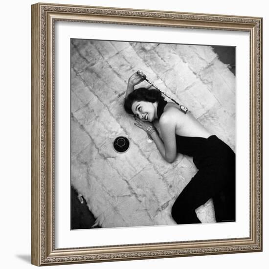 Woman using pearls and seashell covered back scratcher across white plush rug-Yale Joel-Framed Photographic Print