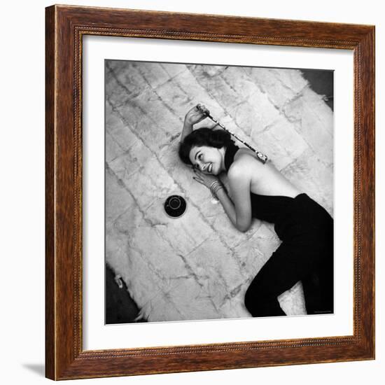 Woman using pearls and seashell covered back scratcher across white plush rug-Yale Joel-Framed Photographic Print