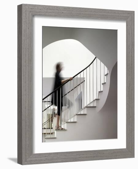 Woman walking up staircase holding handrail-John Edward Linden-Framed Photo