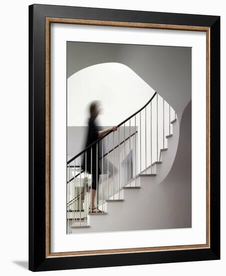 Woman walking up staircase holding handrail-John Edward Linden-Framed Photo