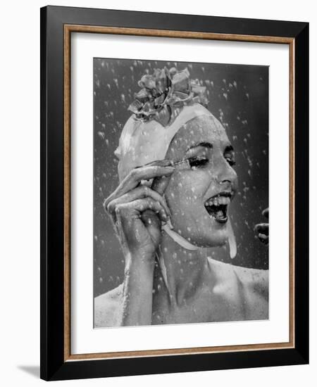 Woman Wearing Flowered Bathing Cap and Applying Mascara as Water Showers Around Her-Gjon Mili-Framed Photographic Print