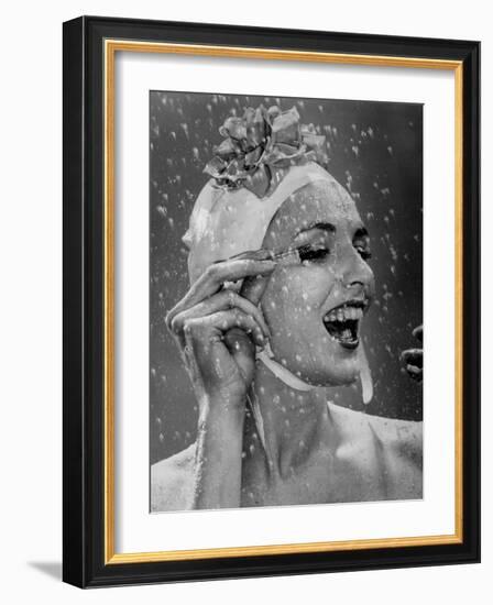 Woman Wearing Flowered Bathing Cap and Applying Mascara as Water Showers Around Her-Gjon Mili-Framed Photographic Print