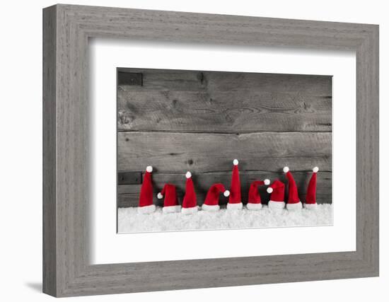 Wooden Christmas Background with Red Santa Hats for a Festive Frame or Card.-Imagesbavaria-Framed Premium Photographic Print