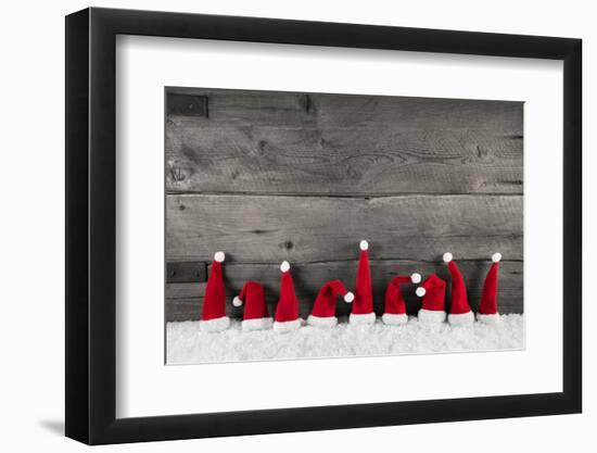 Wooden Christmas Background with Red Santa Hats for a Festive Frame or Card.-Imagesbavaria-Framed Premium Photographic Print