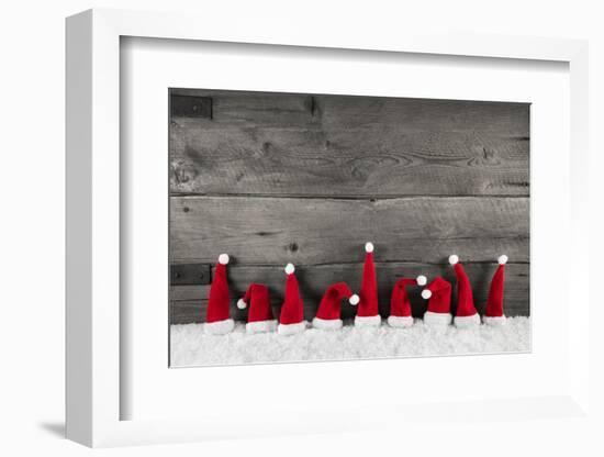 Wooden Christmas Background with Red Santa Hats for a Festive Frame or Card.-Imagesbavaria-Framed Premium Photographic Print