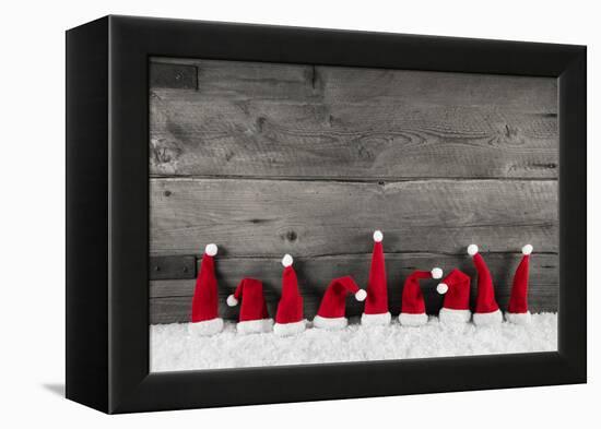 Wooden Christmas Background with Red Santa Hats for a Festive Frame or Card.-Imagesbavaria-Framed Premier Image Canvas