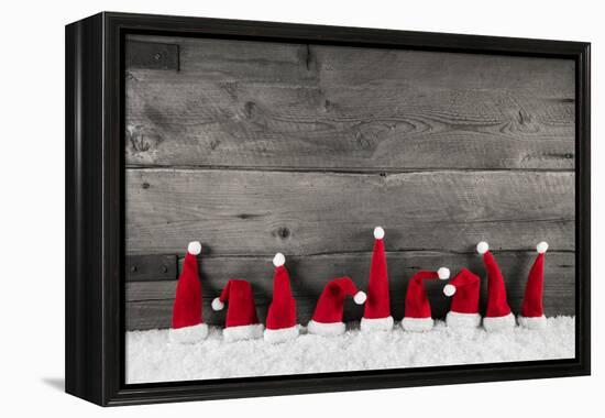 Wooden Christmas Background with Red Santa Hats for a Festive Frame or Card.-Imagesbavaria-Framed Premier Image Canvas