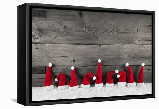 Wooden Christmas Background with Red Santa Hats for a Festive Frame or Card.-Imagesbavaria-Framed Premier Image Canvas