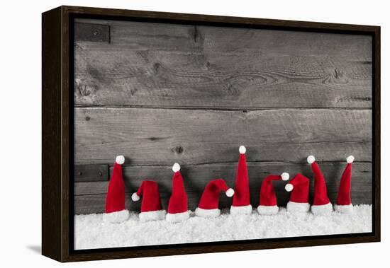 Wooden Christmas Background with Red Santa Hats for a Festive Frame or Card.-Imagesbavaria-Framed Premier Image Canvas