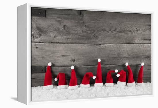 Wooden Christmas Background with Red Santa Hats for a Festive Frame or Card.-Imagesbavaria-Framed Premier Image Canvas