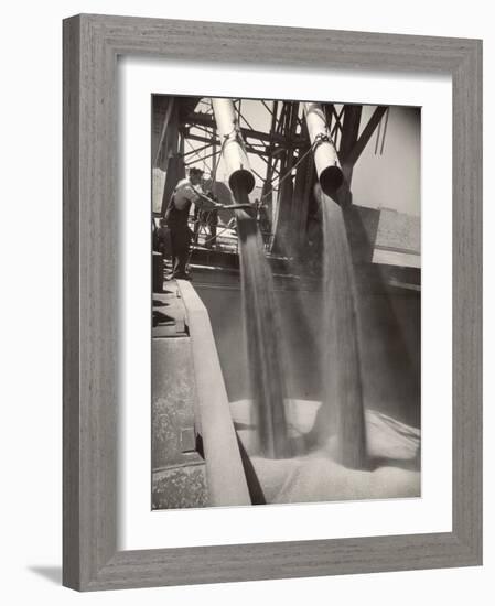 Workers Guiding Granary Filling Spouts as They Pour Tons of Wheat into River Barge for Shipment-Margaret Bourke-White-Framed Photographic Print