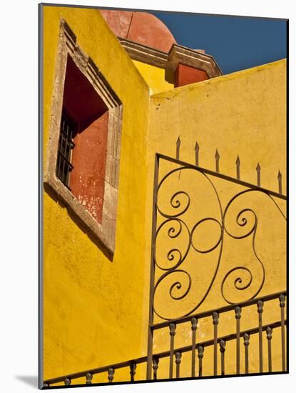 Wrought Iron Fence Against a Yellow Church Wall with Barred Window Against a Blue Sky, Mexico-Judith Zimmerman-Mounted Photographic Print