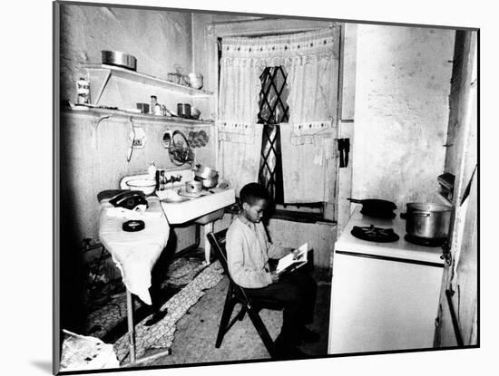 Young African American Studies by Kitchen Stove Because His Apartment Is Without Heat-null-Mounted Photo