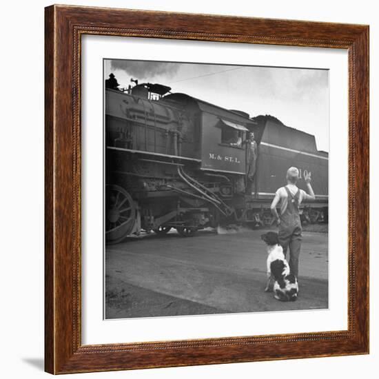 Young Boy and His Dog Standing at the Crossing as a Train Rides Through-Myron Davis-Framed Photographic Print