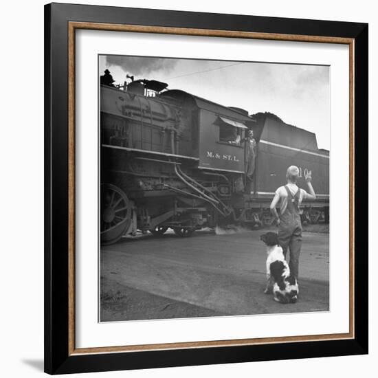 Young Boy and His Dog Standing at the Crossing as a Train Rides Through-Myron Davis-Framed Photographic Print