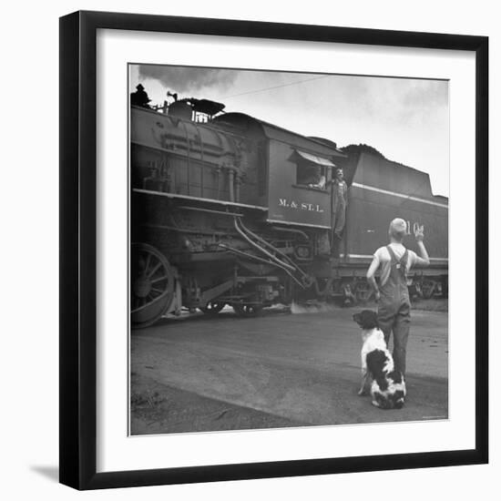 Young Boy and His Dog Standing at the Crossing as a Train Rides Through-Myron Davis-Framed Photographic Print