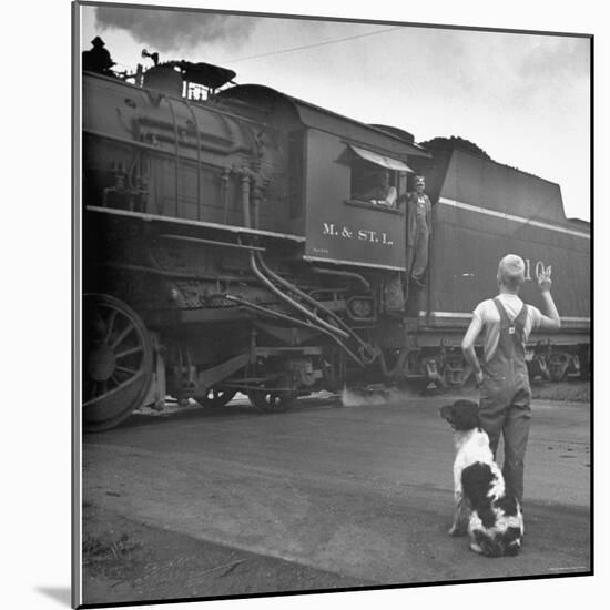 Young Boy and His Dog Standing at the Crossing as a Train Rides Through-Myron Davis-Mounted Photographic Print