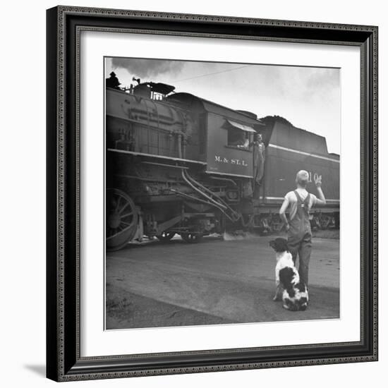 Young Boy and His Dog Standing at the Crossing as a Train Rides Through-Myron Davis-Framed Photographic Print