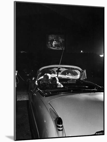 Young Couple Cuddling as They Watch a Movie at Drive in Theater-Francis Miller-Mounted Photographic Print
