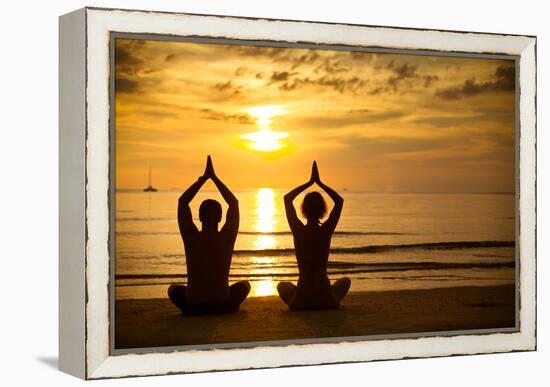 Young Couple Practicing Yoga On The Sea Beach At Sunset-De Visu-Framed Stretched Canvas