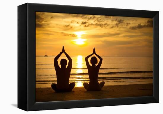 Young Couple Practicing Yoga On The Sea Beach At Sunset-De Visu-Framed Stretched Canvas