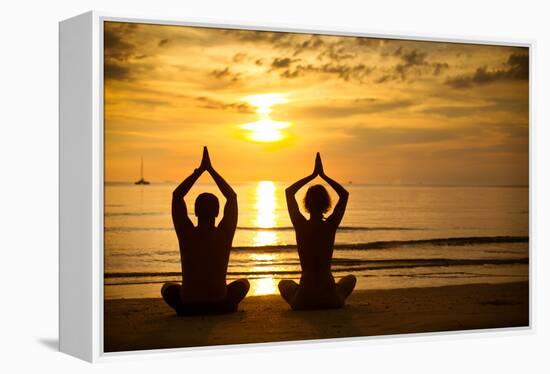 Young Couple Practicing Yoga On The Sea Beach At Sunset-De Visu-Framed Stretched Canvas