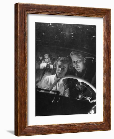 Young Couple Snuggling in Convertible as They Intently Watch Movie at Drive-in Movie Theater-J^ R^ Eyerman-Framed Photographic Print