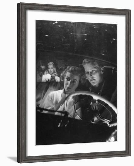 Young Couple Snuggling in Convertible as They Intently Watch Movie at Drive-in Movie Theater-J^ R^ Eyerman-Framed Photographic Print