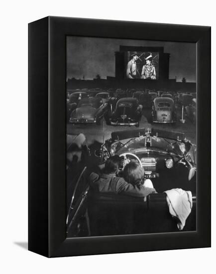 Young Couple Snuggling in Convertible as They Watch Large Screen Action at a Drive-In Movie Theater-J^ R^ Eyerman-Framed Premier Image Canvas