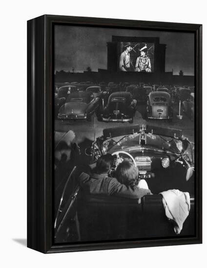 Young Couple Snuggling in Convertible as They Watch Large Screen Action at a Drive-In Movie Theater-J^ R^ Eyerman-Framed Premier Image Canvas