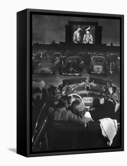 Young Couple Snuggling in Convertible as They Watch Large Screen Action at a Drive-In Movie Theater-J^ R^ Eyerman-Framed Premier Image Canvas