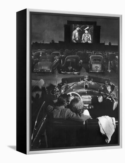 Young Couple Snuggling in Convertible as They Watch Large Screen Action at a Drive-In Movie Theater-J^ R^ Eyerman-Framed Premier Image Canvas