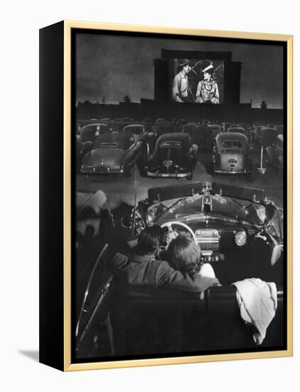 Young Couple Snuggling in Convertible as They Watch Large Screen Action at a Drive-In Movie Theater-J^ R^ Eyerman-Framed Premier Image Canvas