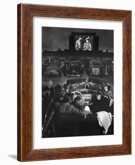 Young Couple Snuggling in Convertible as They Watch Large Screen Action at a Drive-In Movie Theater-J. R. Eyerman-Framed Photographic Print