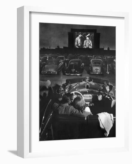 Young Couple Snuggling in Convertible as They Watch Large Screen Action at a Drive-In Movie Theater-J^ R^ Eyerman-Framed Photographic Print