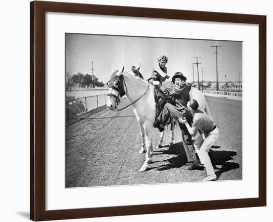 Young Couple Trying to Help a Man Get onto His Horse-null-Framed Photo