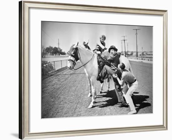 Young Couple Trying to Help a Man Get onto His Horse-null-Framed Photo