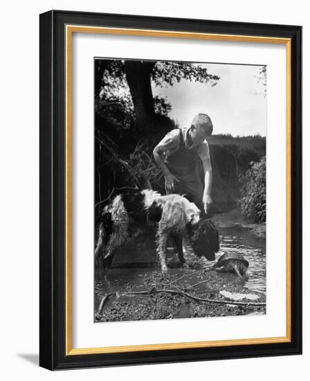 Young Farm Boy Watching His Dog Sniff a Large Turtle at the Pond-Myron Davis-Framed Photographic Print