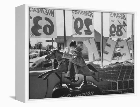 Young Girl Sitting on a Coin Rider Reading a Comic Book at the Supermarket-Dmitri Kessel-Framed Premier Image Canvas