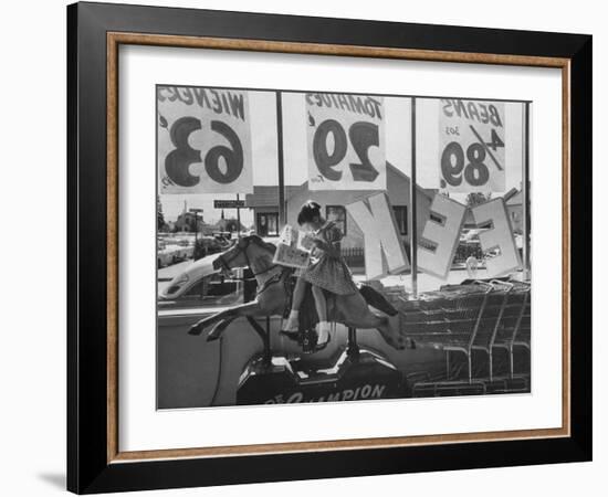 Young Girl Sitting on a Coin Rider Reading a Comic Book at the Supermarket-Dmitri Kessel-Framed Photographic Print