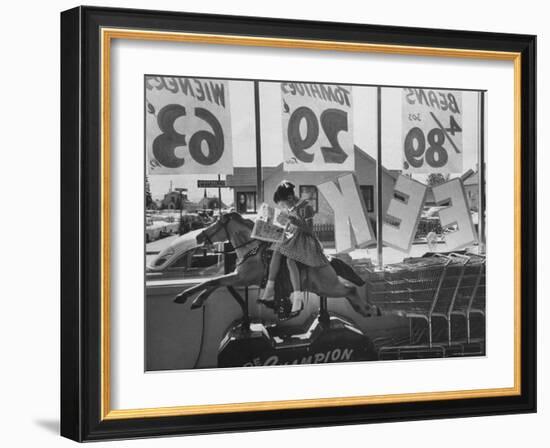 Young Girl Sitting on a Coin Rider Reading a Comic Book at the Supermarket-Dmitri Kessel-Framed Photographic Print