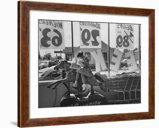 Young Girl Sitting on a Coin Rider Reading a Comic Book at the Supermarket-Dmitri Kessel-Framed Photographic Print