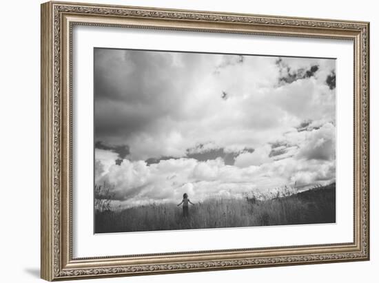 Young Girl Standing in a Field with Clouds-Clive Nolan-Framed Photographic Print