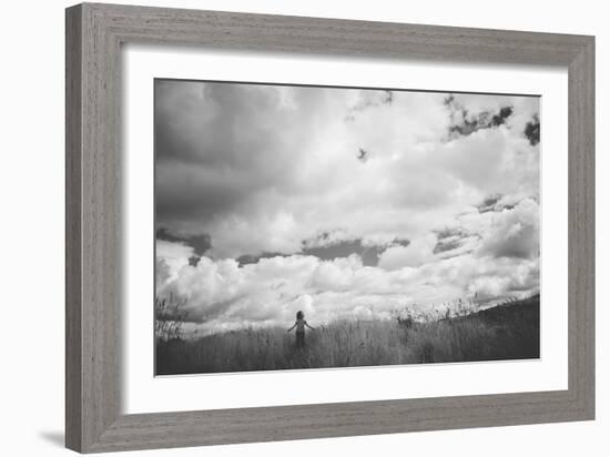 Young Girl Standing in a Field with Clouds-Clive Nolan-Framed Photographic Print