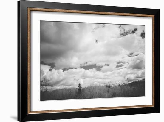 Young Girl Standing in a Field with Clouds-Clive Nolan-Framed Photographic Print