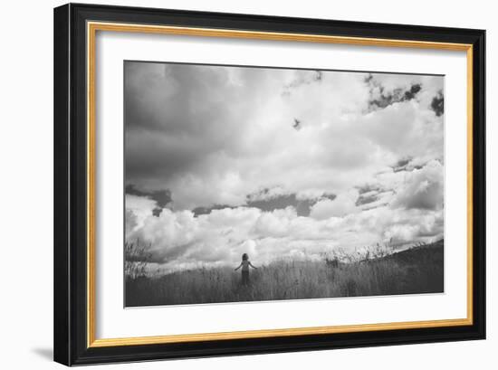 Young Girl Standing in a Field with Clouds-Clive Nolan-Framed Photographic Print