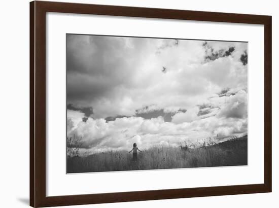 Young Girl Standing in a Field with Clouds-Clive Nolan-Framed Photographic Print