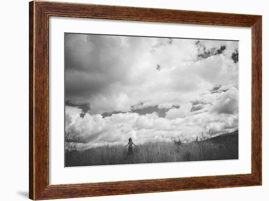 Young Girl Standing in a Field with Clouds-Clive Nolan-Framed Photographic Print